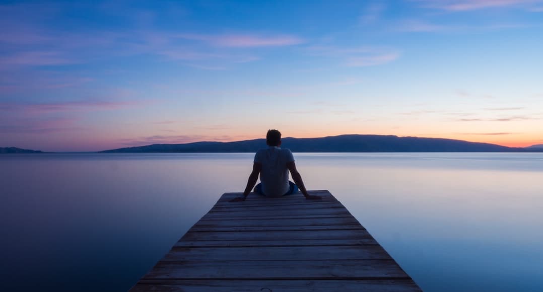 Person watching the sunset to illustrate the tension release of planning for your financial future.