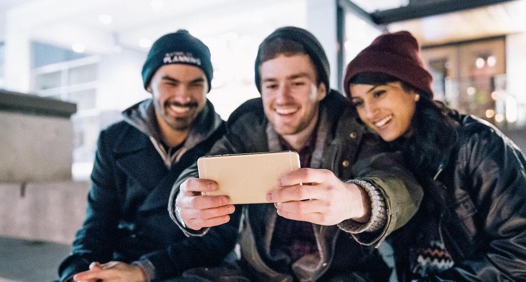 Friends taking a selfie to illustrate how you can invest in happiness via a supportive community.