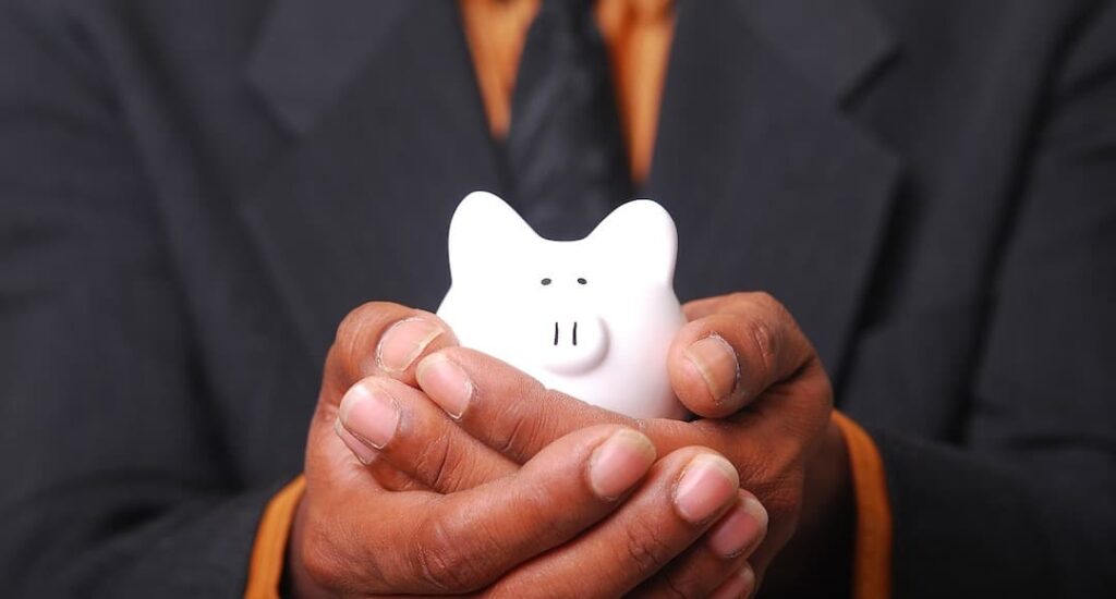 Business person holding a piggy bank to illustrate the common tax mistake of failing to take full advantage of tax advantaged savings.